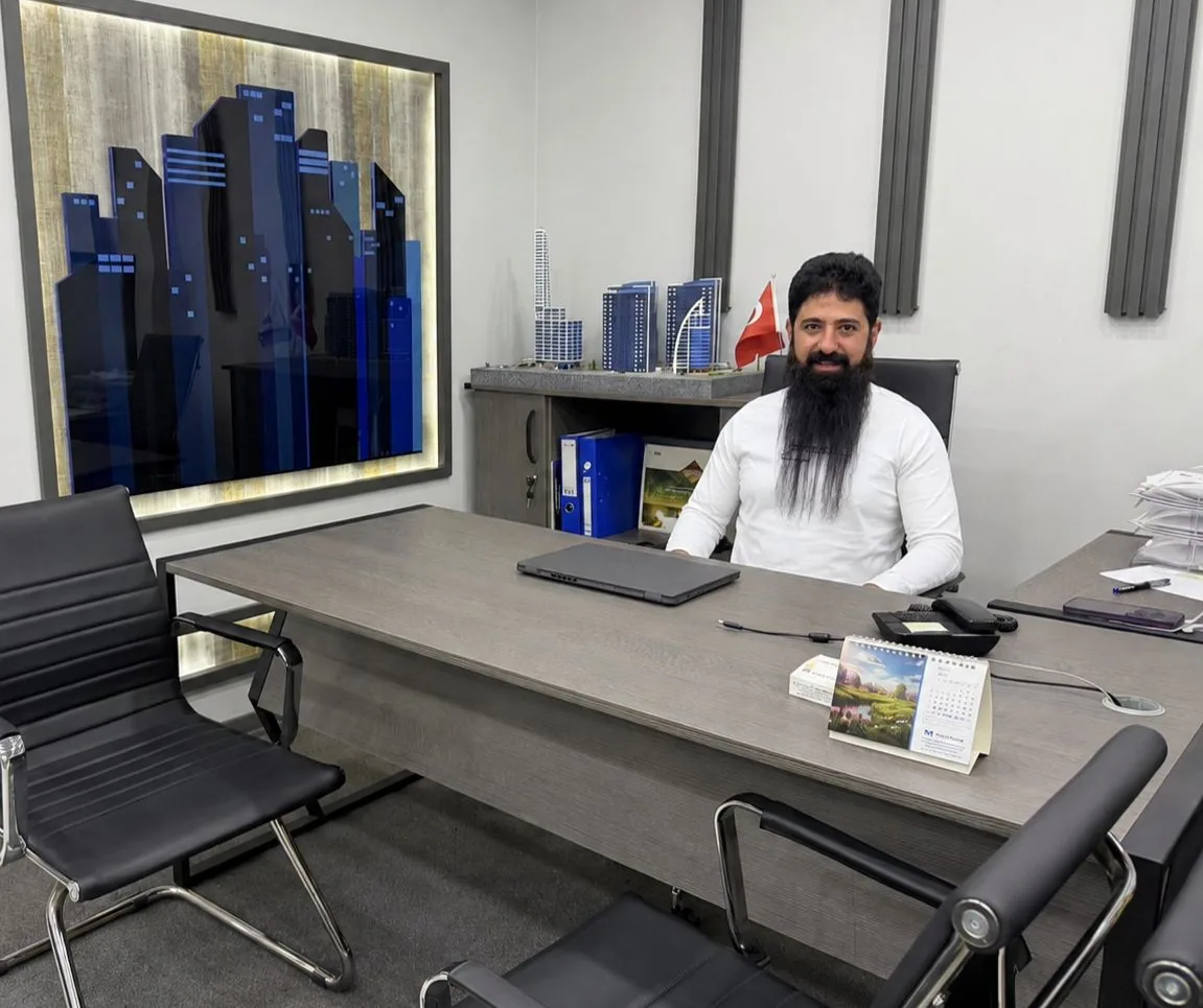 A team member at his desk, beside the project models and the city artwork